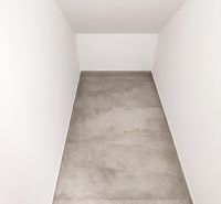 A narrow office space with white walls and a gray floor.