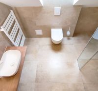 Bathroom with a toilet, shower, sink, and modern flooring with a wood design.