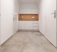 Minimalist white kitchen unit in an office with wood-decor flooring.