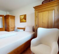 A bedroom in a family house with wooden furniture and a comfortable armchair.