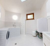 A spacious bathroom in a family house with a bathtub, washing machine, and gas boiler.