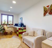 A spacious office with a sofa and a desk, a floor with a wooden decor, houseplants.