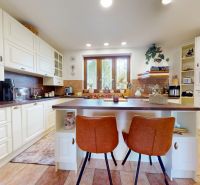 A kitchen in a family house with white cabinets and bar stools.
