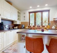 A kitchen in a family house with white cabinets and a wooden decor on the countertop.