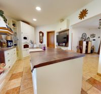 The interior of a kitchen in a family house, white cabinets and a large kitchen countertop.