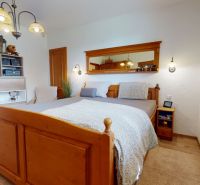 A bedroom in a family house with a wooden bed and a floor with a wooden decor.