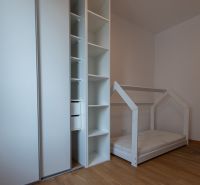 Children's room with a house-shaped bed, wardrobe, and wooden decor flooring.