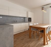 A kitchen in a 3-room apartment with a wooden decor floor and a dining table.