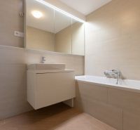 A bathroom with a bathtub and a sink in a 3-room apartment, light tiles on the walls.