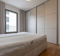 A bedroom with a large window, a built-in wardrobe, and a bed in a 3-room apartment.