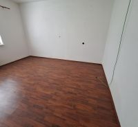 An empty room with laminate flooring and white walls in a family house.