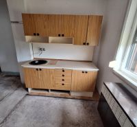 Wooden kitchen unit with a sink in the interior of a family house with low cabinets.