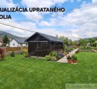 A family house in Stožok with a wooden shelter, green grass, and flowers in the garden.