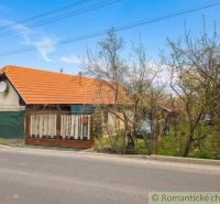 A family house in Stožok with a red roof, a fence, and a garden near the road.