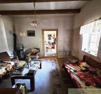 Living room in a cottage with a sofa, carpet, table, and wooden beams on the ceiling.