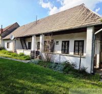 A traditional cottage in the town of Šahy with a white facade and a garden full of greenery.