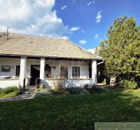 A cottage in Šahy with white walls and a traditional roof surrounded by greenery.