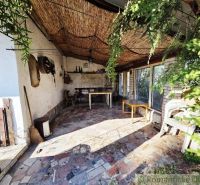 Covered terrace of the cottage in Šahy with a colorful stone floor and natural decorations.