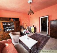 A living room in a family house with pink walls and wooden furniture.