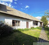 A cottage in Šahy with a white facade, a sloping roof, and a paved walkway.