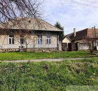 A cottage in Šahy surrounded by a lawn and trees, with an older roof.