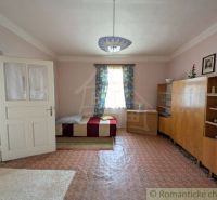 A room with simple furniture, a bed, and carpets in a family house.