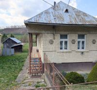 A family house in Zubné with a metal roof, a veranda, and surrounding lawn.