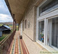 A balcony of a family house in Zubné with a view of wooden buildings and the countryside.