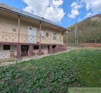 A family house in Zubné with a large veranda, green lawn, and slope.