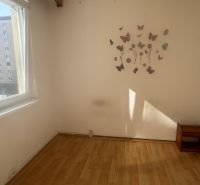 A room in a three-room apartment with a wooden decor floor and butterfly stickers on the wall.
