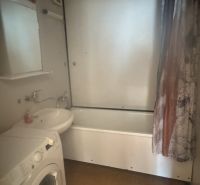 A bathroom in a 3-room apartment with a bathtub and a washing machine, bright tiles.