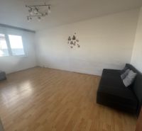 Living room with wood-patterned flooring, a sofa, and a large window in a three-room apartment.