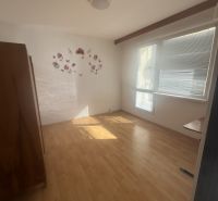 A room with a light wooden floor, a window, and light decoration on the wall.