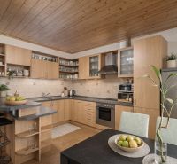 A kitchen in a family house with a wooden ceiling, a dining area, and modern equipment.