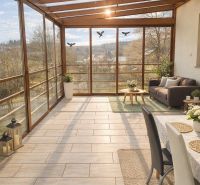 Glazed terrace of a family house with a wooden decor floor and a view of nature.