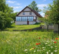 A family house in Oravská Lesná bordered by a flowery meadow and a wooden fence.