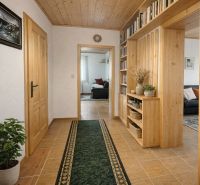 A hallway in a family house with wooden decor and a green carpet, cozy environment.