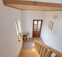 A family house with a staircase and wooden decor, flowers, and warm interior tones.