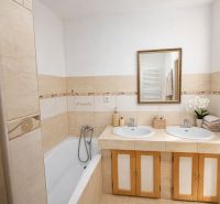 A bathroom in a family house with a bathtub, two sinks, and a mirror above them.