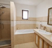 A bathroom in a family house with a bathtub, shower, sink, and window.