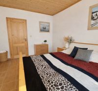 Bedroom in a family house with a wooden ceiling and a patterned bedspread.