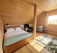 A bedroom in a family house with a bed, sofa, carpet, and wooden decor flooring.