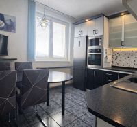 A modern kitchen with dark furniture and built-in appliances in a 3-room apartment.