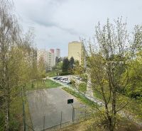 A view of the housing estate in Trenčín on Mateja Bela with a parking lot and a playground between the apartment buildings.