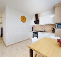 A kitchen with white cabinets, wooden decor, and a table in a three-room apartment.