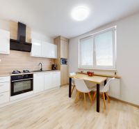A kitchen in a 3-room apartment with a wooden decor floor and light furniture.