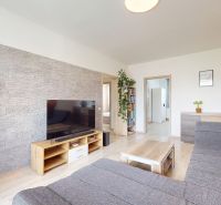Living room with a TV, sofa, and a wall with stone decor in a 3-room apartment.