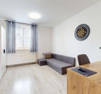 Living room in a 3-room apartment with a wooden decor floor, a sofa, and a desk.