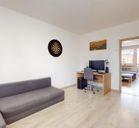 Living room in a three-room apartment with a gray sofa and a desk.