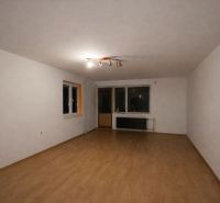 A spacious room in a family house with white walls and a wooden decor floor.